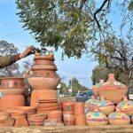 A vendor arranging and displaying clay made pot at his setup in the Federal Capital