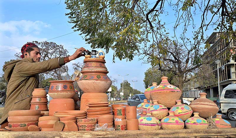 A vendor arranging and displaying clay made pot at his setup in the Federal Capital