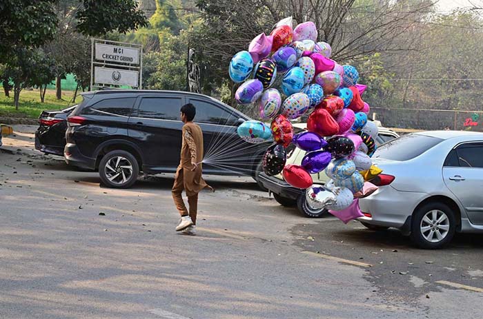 A vendor displaying colorful balloons while shuttling on road at F-7 Markaz in Federal Capital.