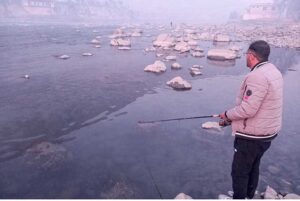 Youngster catching fish on the bank of river Gilgit.