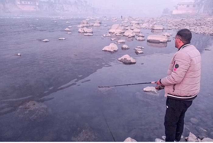 Youngster catching fish on the bank of river Gilgit. Youngster catching fish on the bank of river Gilgit.