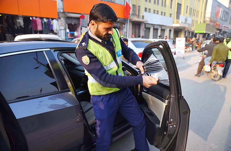 Traffic Warden Officials are removing tinted sheet from a car at Cantt Bazar.