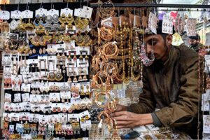 A vendor displaying artificial jewelry to attract the customers at Shahi Bazar. 