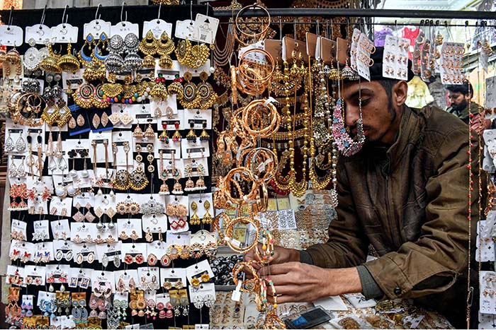 A vendor displaying artificial jewelry to attract the customers at Shahi Bazar.
