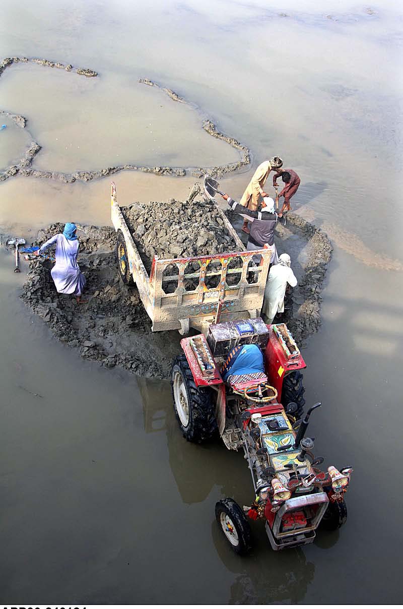 Labourers busy in loading sand on tractor trolley from Rice Canal