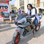 Female student sit in heavy motorbike during auto show at Isra University.