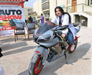 Female student sit in heavy motorbike during auto show at Isra University.
