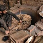 A worker busy in roasting the peanuts for customers at his workplace.