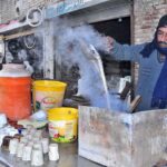 A vendor is preparing tea for customers during cold weather at Tariqabad Road.