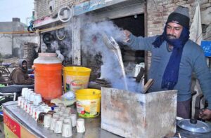 A vendor is preparing tea for customers during cold weather at Tariqabad Road.