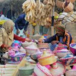 A lady purchasing different kinds of handmade items from a roadside vendor.
