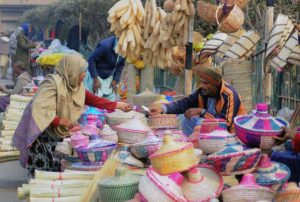 A lady purchasing different kinds of handmade items from a roadside vendor.