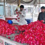 Vendors making flower garlands to attract the customers at roadside setup