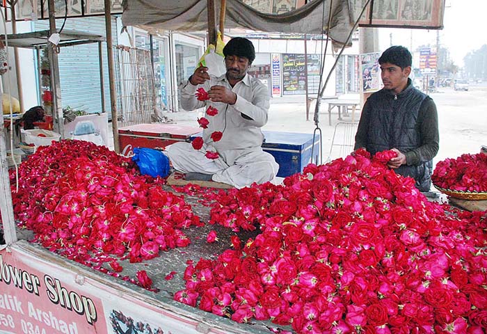 Vendors making flower garlands to attract the customers at roadside setup