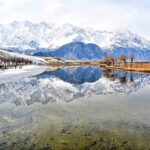 Attractive and eye catching view of reflection of snow covered mountain and leafless tree's in Katpana Desert Lake in the catchment area of Pakistan
