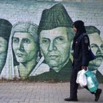 A woman on her way while portraits of national leaders on a school wall attracts people at Supper Market area.