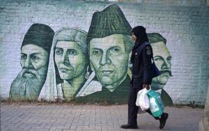 A woman on her way while portraits of national leaders on a school wall attracts people at Supper Market area.