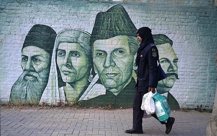A woman on her way while portraits of national leaders on a school wall attracts people at Supper Market area. A woman on her way while portraits of national leaders on a school wall attracts people at Supper Market area.