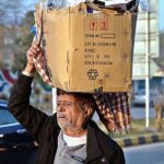 An aged person on his way carrying heavy load on his head at Supper Market area.