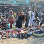 People selecting and purchasing household items from a roadside vendor