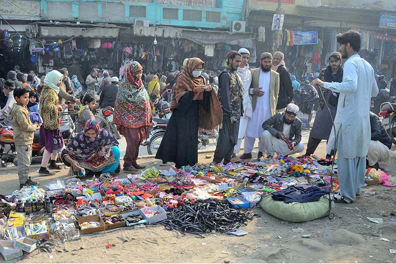 People selecting and purchasing household items from a roadside vendor