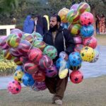 A vendor carrying balloons, shuttling in a local park to earn for livelihood.