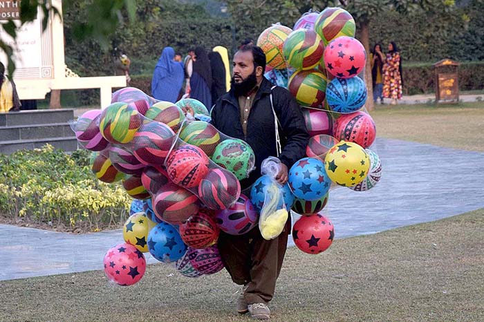 A vendor carrying balloons, shuttling in a local park to earn for livelihood.