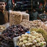 A vendor waiting for customers while displaying different kinds of Dry Fruits on the roadside setup at local market.