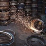 A worker busy in repairing the secondhand vehicles tyre rims at his workplace