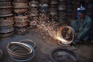 A worker busy in repairing the secondhand vehicles tyre rims at his workplace