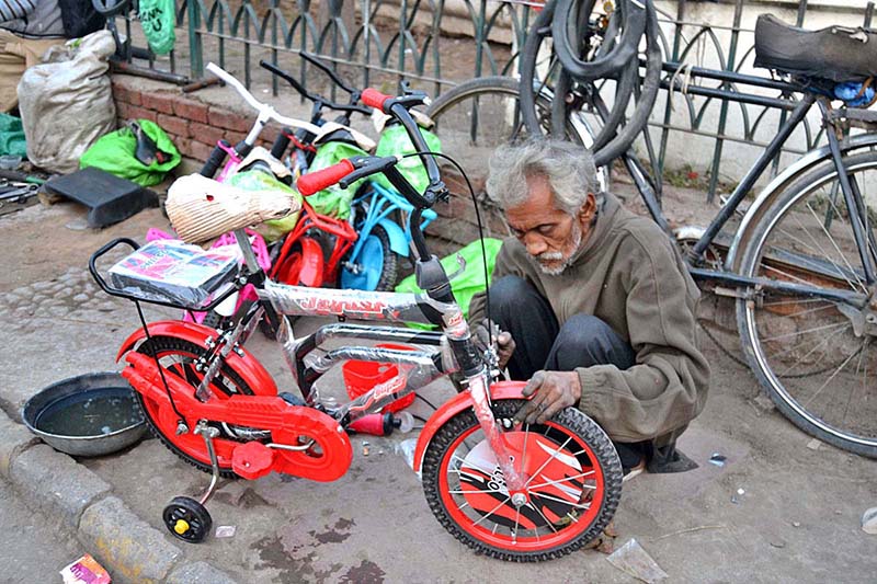 An elderly man is engrossed in repairing bicycles on the footpath in Anarkali Bazaar