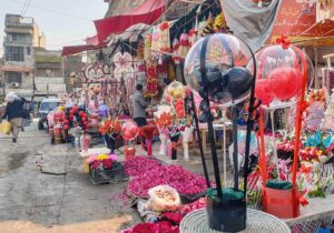 Vendors displaying roses and flower bouquet to attract customers outside their shops at Bani Chowk. 