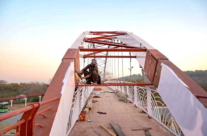 A welder finishing grills of a new pedestrian bridge over the Srinagar Highway in the federal capital.