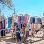 A vendor displaying second-hand clothes to attract customers at Khanna Pul