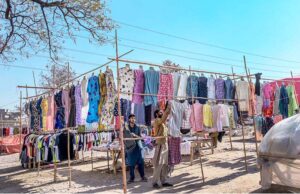 A vendor displaying second-hand clothes to attract customers at Khanna Pul