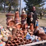A vendor arranging and displaying clay made items to attract customers at his roadside setup at H-9 in the Federal Capital