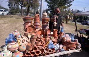 A vendor arranging and displaying clay made items to attract customers at his roadside setup at H-9 in the Federal Capital