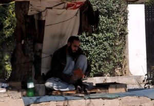 A cobbler is sitting under a tree Polishing a shoes