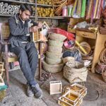 An artisan busy in preparing decorated baskets at his shop in Saddar.