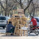 A street hawker sitting on the roadside while waiting for customers to sell wooden stools at F-7/2.