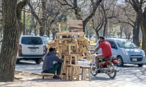 A street hawker sitting on the roadside while waiting for customers to sell wooden stools at F-7/2.