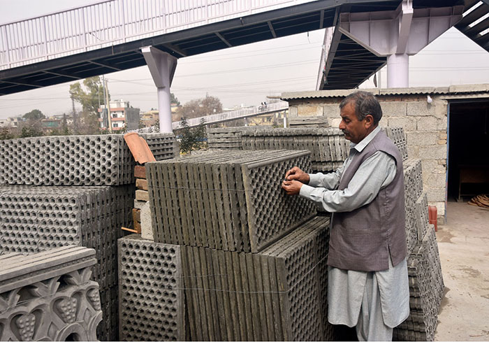 Vendor busy displaying concrete drainage slabs at his setup in the Federal Capital.