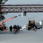worker installing security cameras on pedestrian bridge with the help of crane
