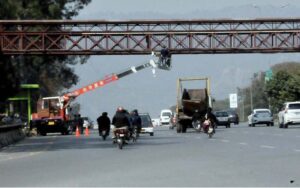 worker installing security cameras on pedestrian bridge with the help of crane