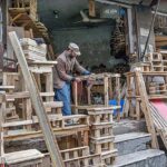 A carpenter busy in preparing wooden stools at his workplace in Banni Market.