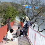 Workers paint the grills of a pedestrian bridge on Srinagar Highway.