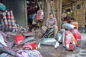 A worker is busy refurbishing the fuel tanks of motorcycles at his workplace in Bhabra Bazaar