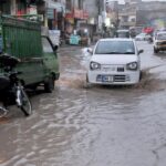 Vehicles passing through rain water accumulated on road at Ghori Town.