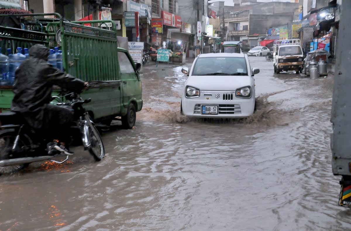 Vehicles passing through rain water accumulated on road at Ghori Town.
