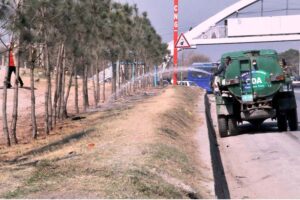 CDA worker busy in watering plants on green belts at Express way